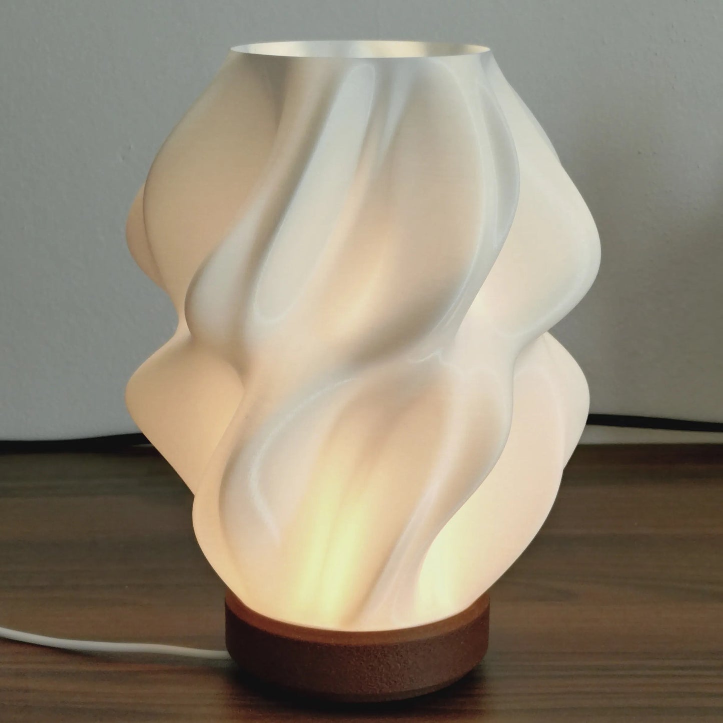 Ovarana Sanjh 3D printed table lamp lit, showing the warm glow through its twisted white shade